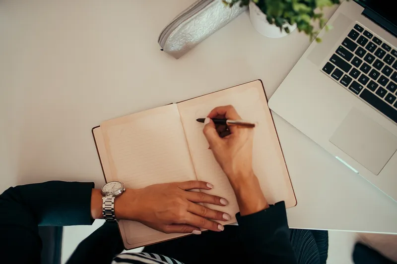 Notes being written beside a laptop