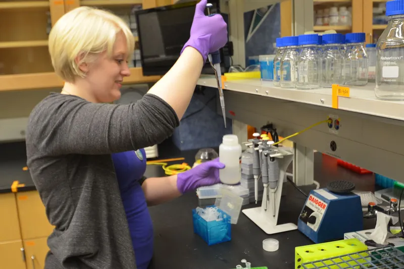 A researcher using a pipette in a university laboratory